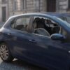Automobil parkiran na ulici s razbijenim bočnim staklom i zrncima stakla na sjedalu i asfaltu